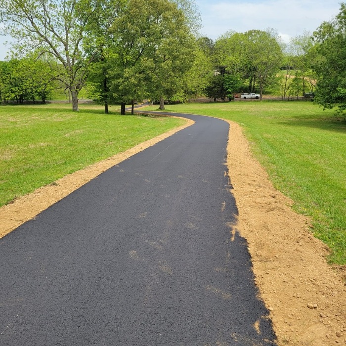 long asphalt driveway through pasture